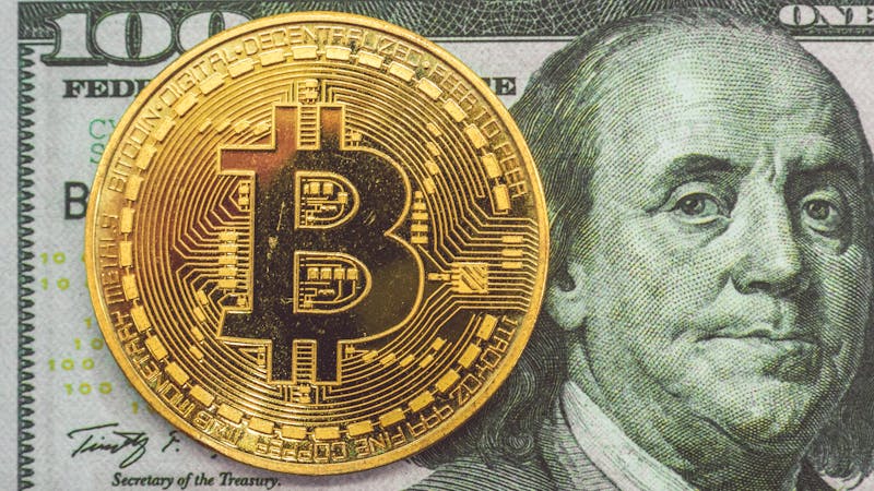 Bitcoin on top a 100 dollar note.