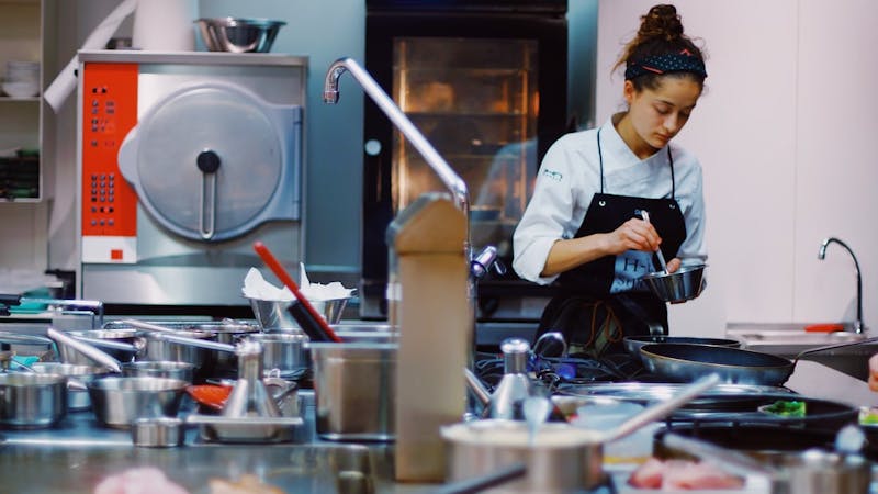 A lady cooking food in the kitchen using different kitchen utensils