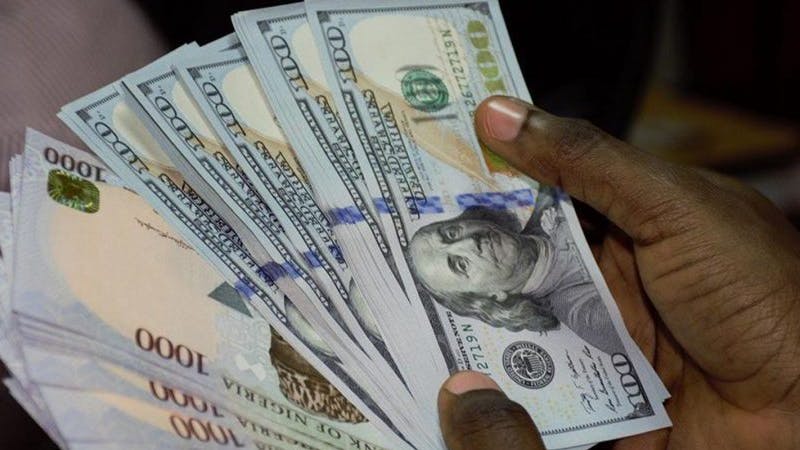Bunch of 100 US dollar bills and 100 Naira bills.