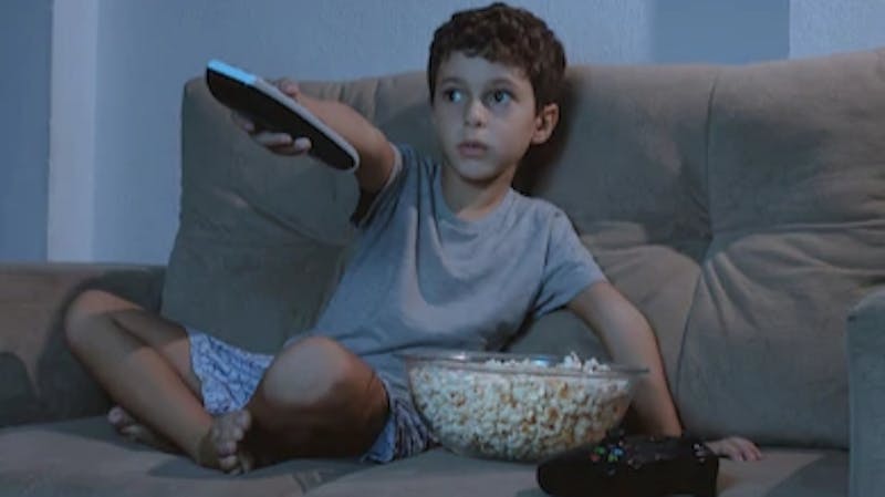 A kid watching TV alone in the living room