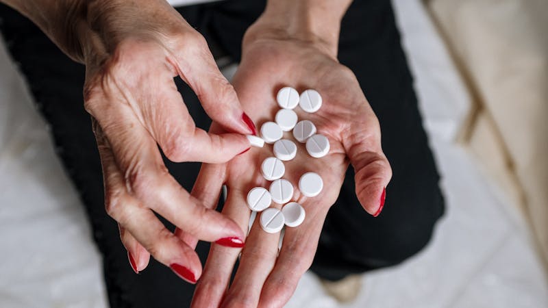 An elderly woman taking expired medicines