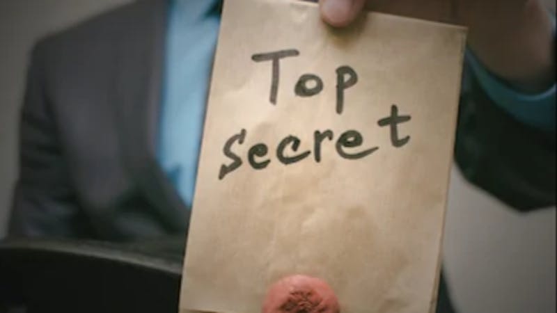 A man holding up a file tagged, "top secret"
