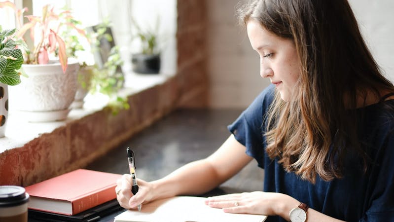 A beautiful lady writing or taking notes on a tablet.