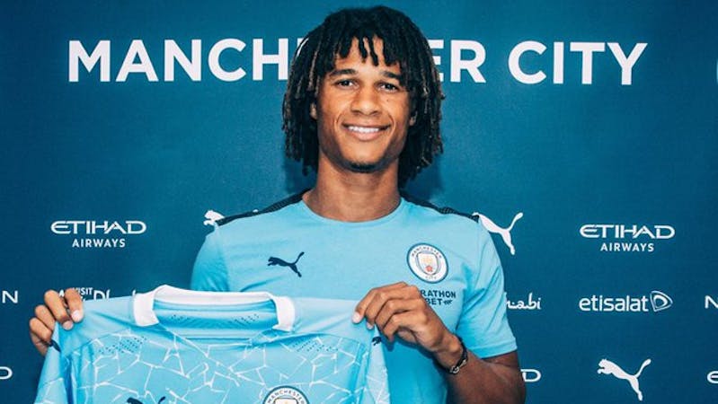 Nathan Ake holding Manchester City shirt after signing for the club