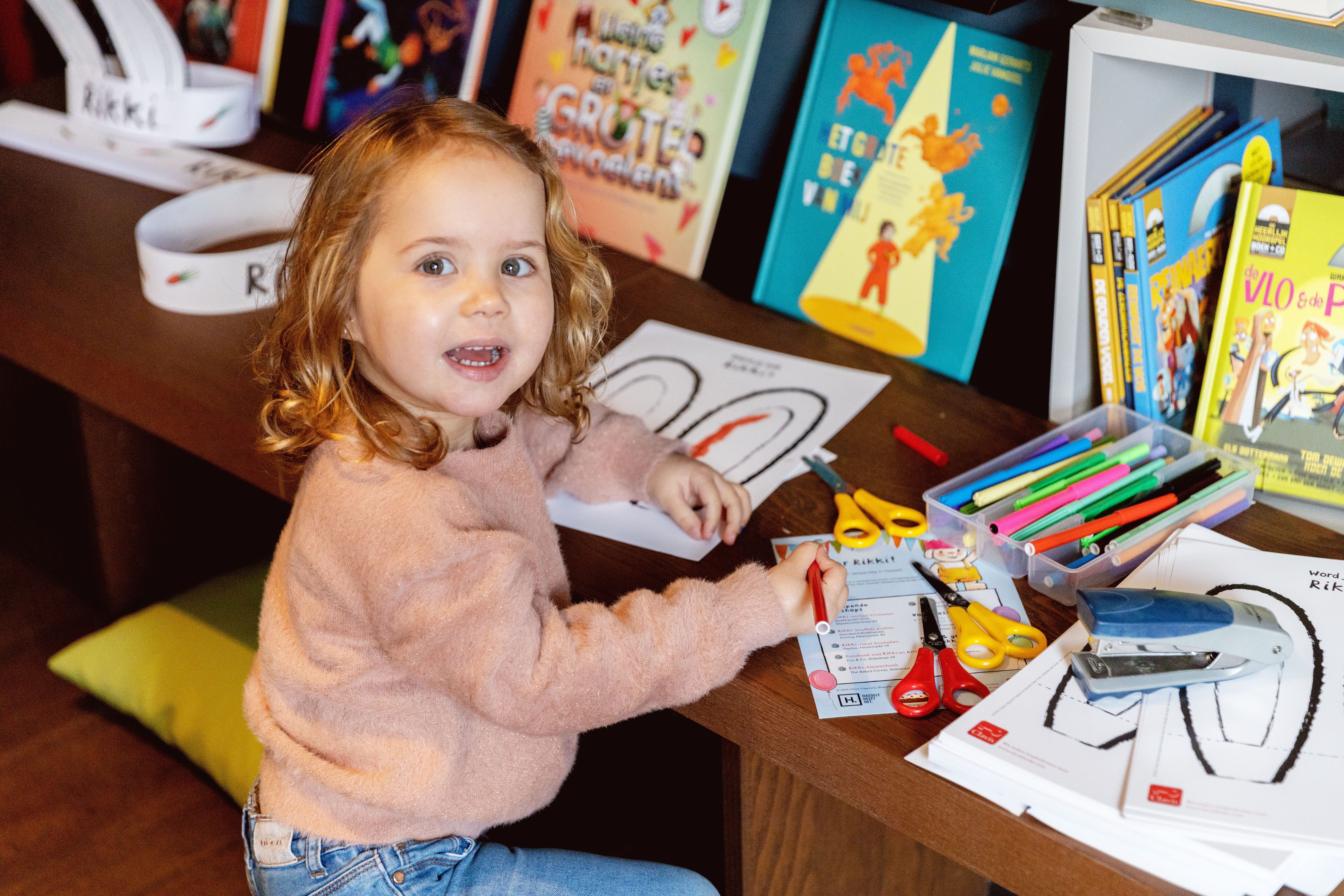 Een kleutertje kleurt Rikki-oortjes aan een bankje in Boekhandel Grim. 