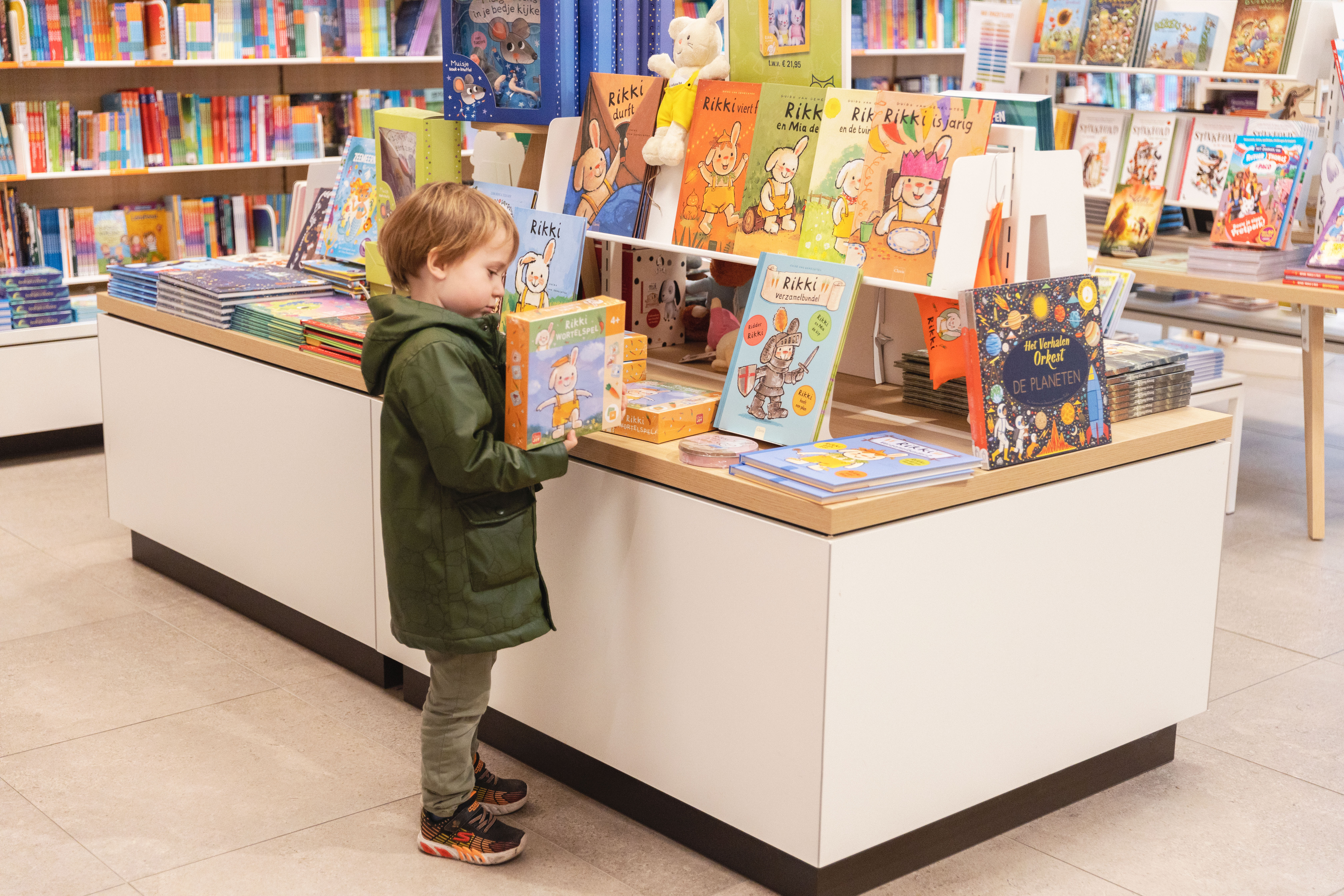 Een kindje bekijkt het Rikki wortelspel in de Standaard Boekhandel. Het spel ligt aan een Rikki-rek waarop alle Rikki producten en boeken liggen uitgestald/ 