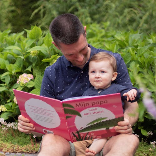 Foto waarop vader en kind samen het boek 'Mijn papa heeft een staart' van Guido Van Genechten lezen.