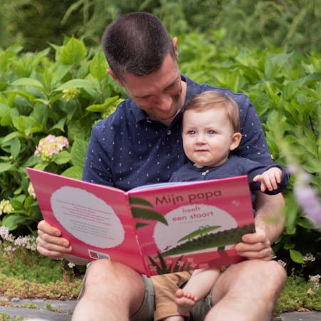 Foto waarop vader en kind samen het boek 'Mijn papa heeft een staart' van Guido Van Genechten lezen.