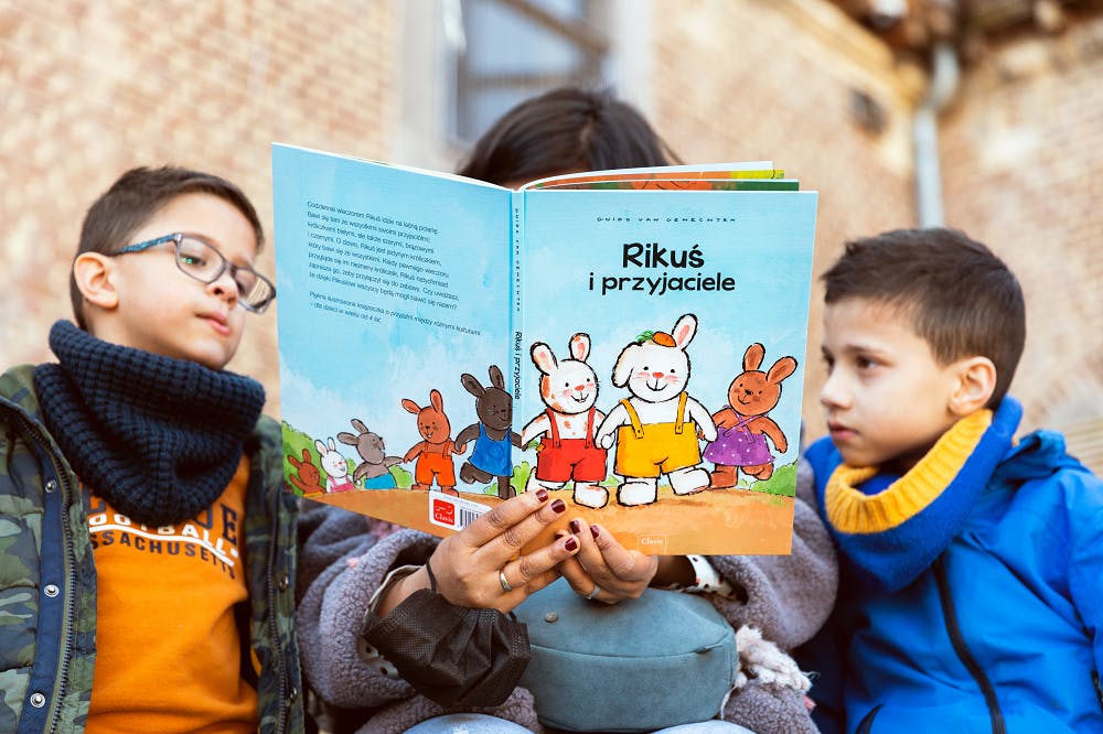 2 jongens worden voorgelezen uit de Roemeense editie van Rikki