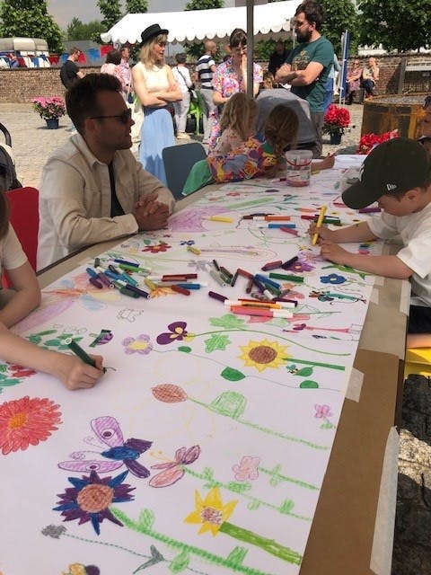kinderen tekenen samen bloemen op een groot papier