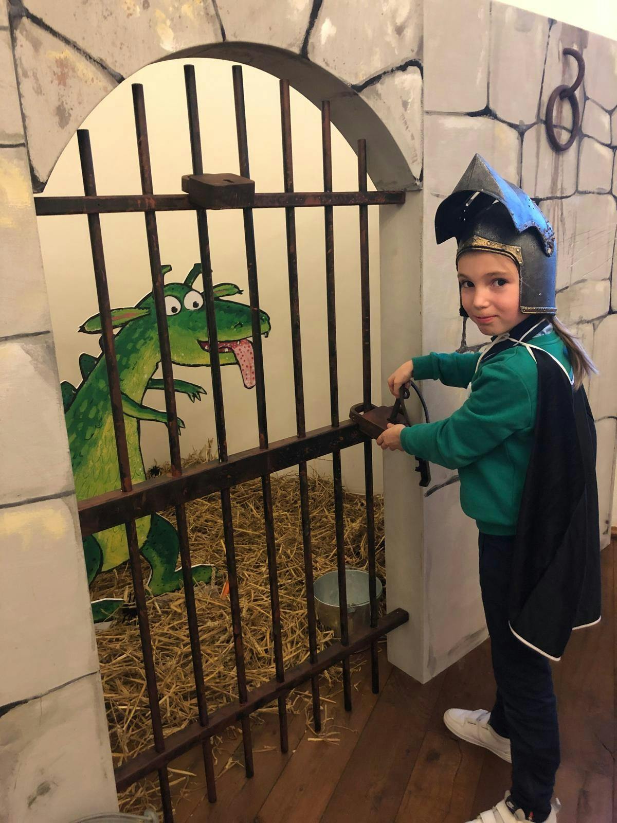 foto van de drakengevangenis van Ridder Rikki, een kind verkleed als ridder probeert het hek op te maken
