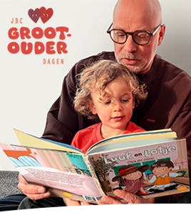 JBC Grootouderdagen. Foto van een opa die aan zijn kleinzoon voorleest uit het boekje Luuk en Lotje. Opa en oma