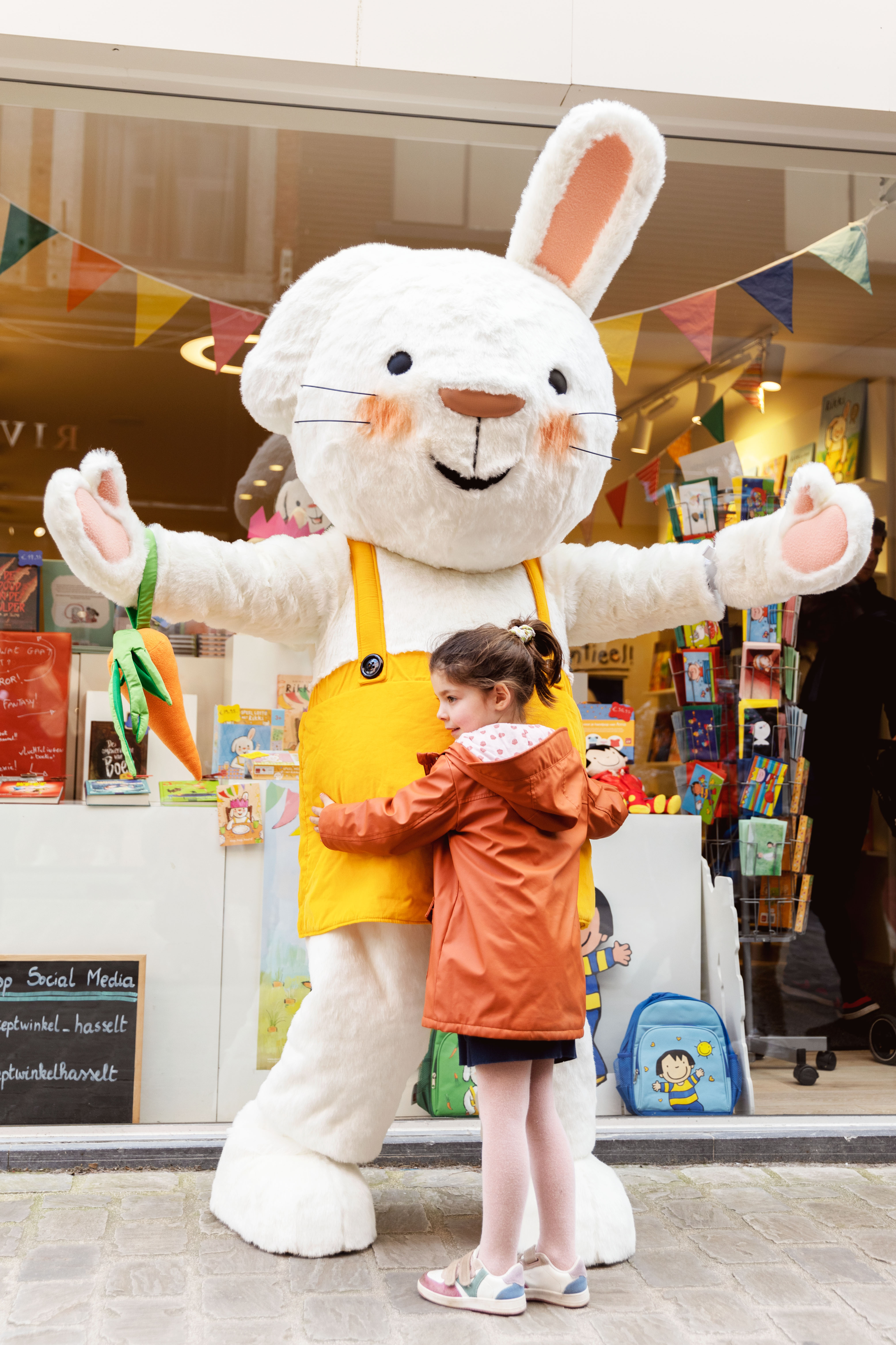 Een foto van een meisje dat Rikki een knuffel geeft aan de Clavis Conceptwinkel Hasselt