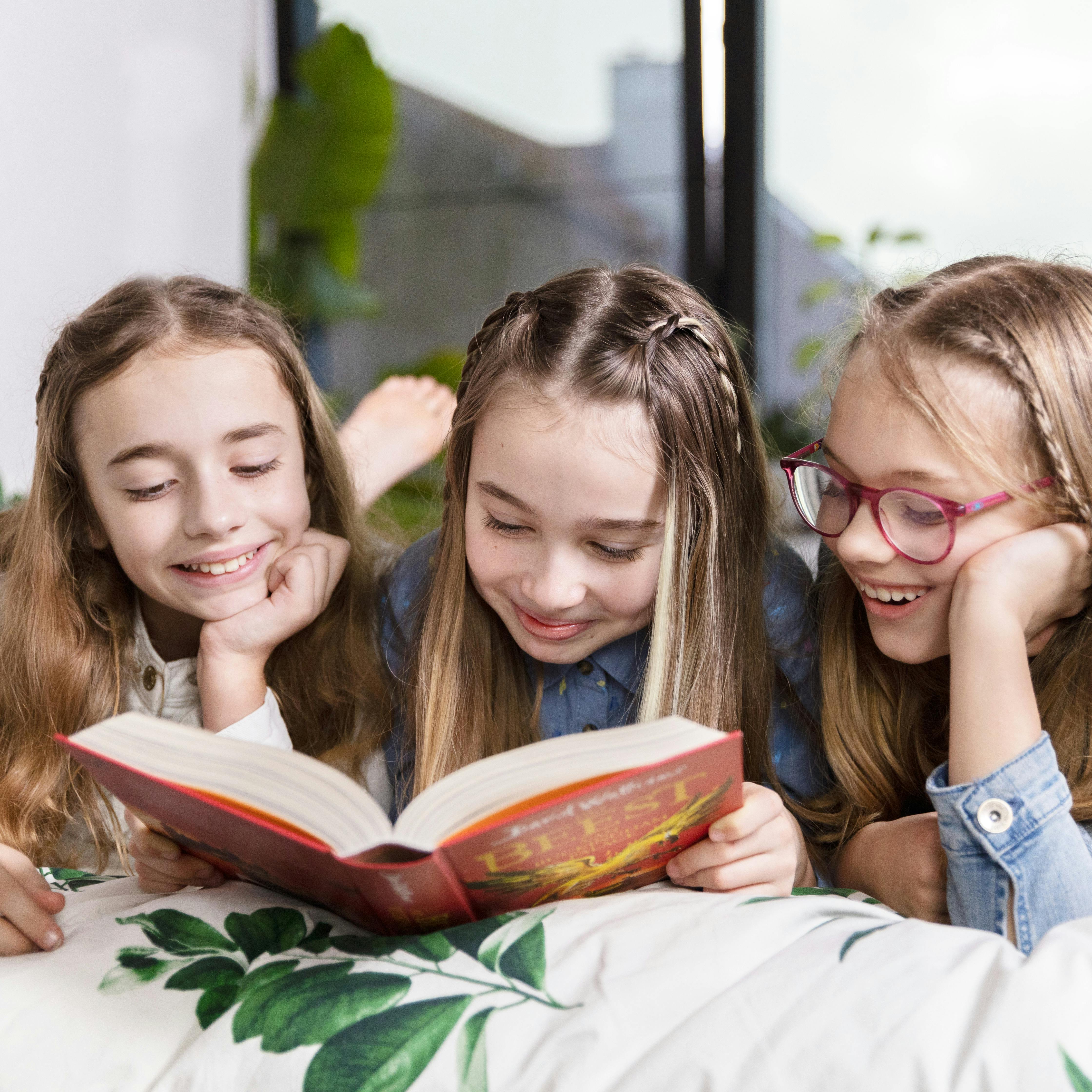 Drie meisjes lezen samen in een boek van David Walliams. 