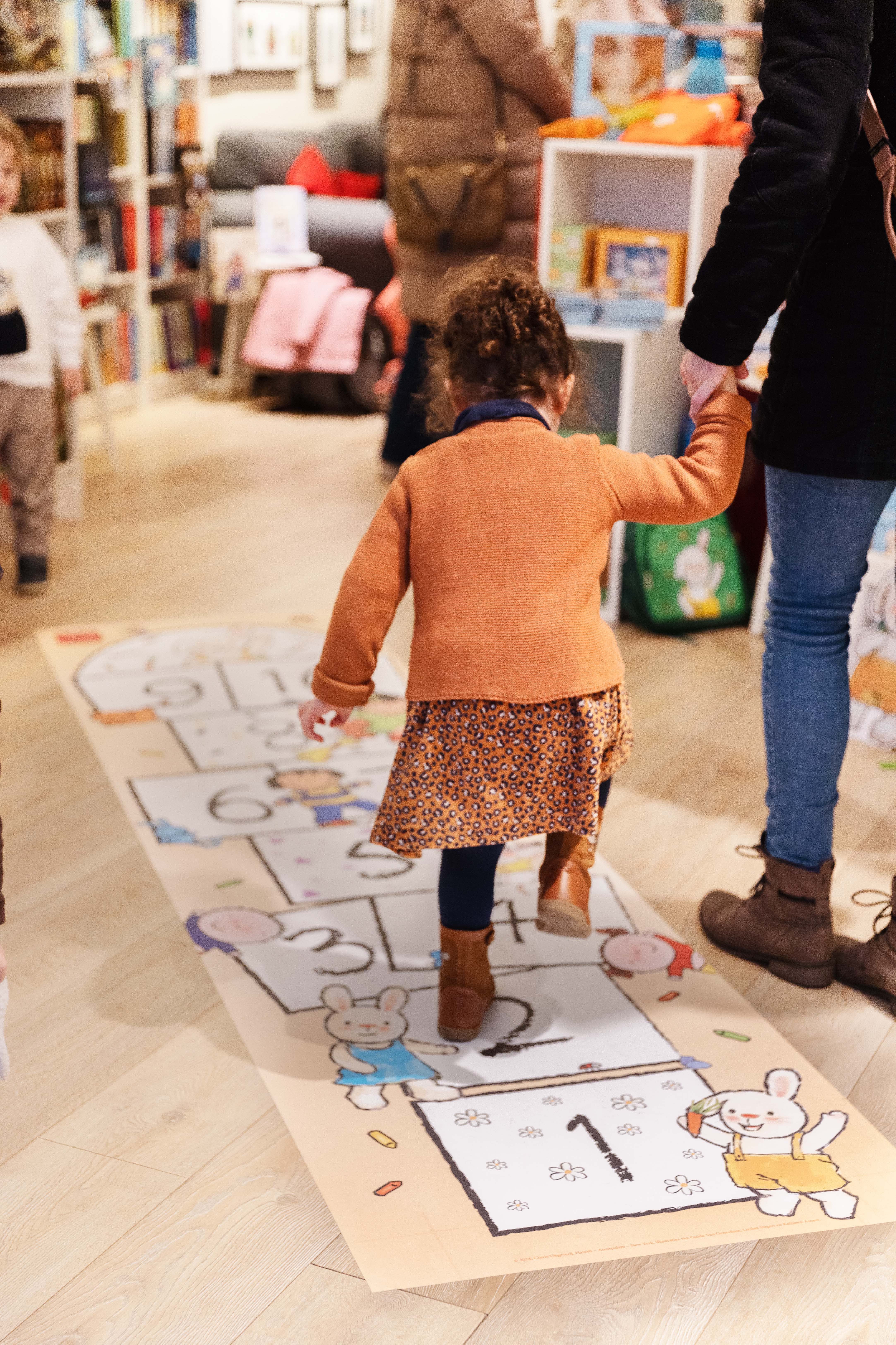 Een kindje springt op het hinkelpad van Clavis in de Clavis Conceptwinkel Hasselt.