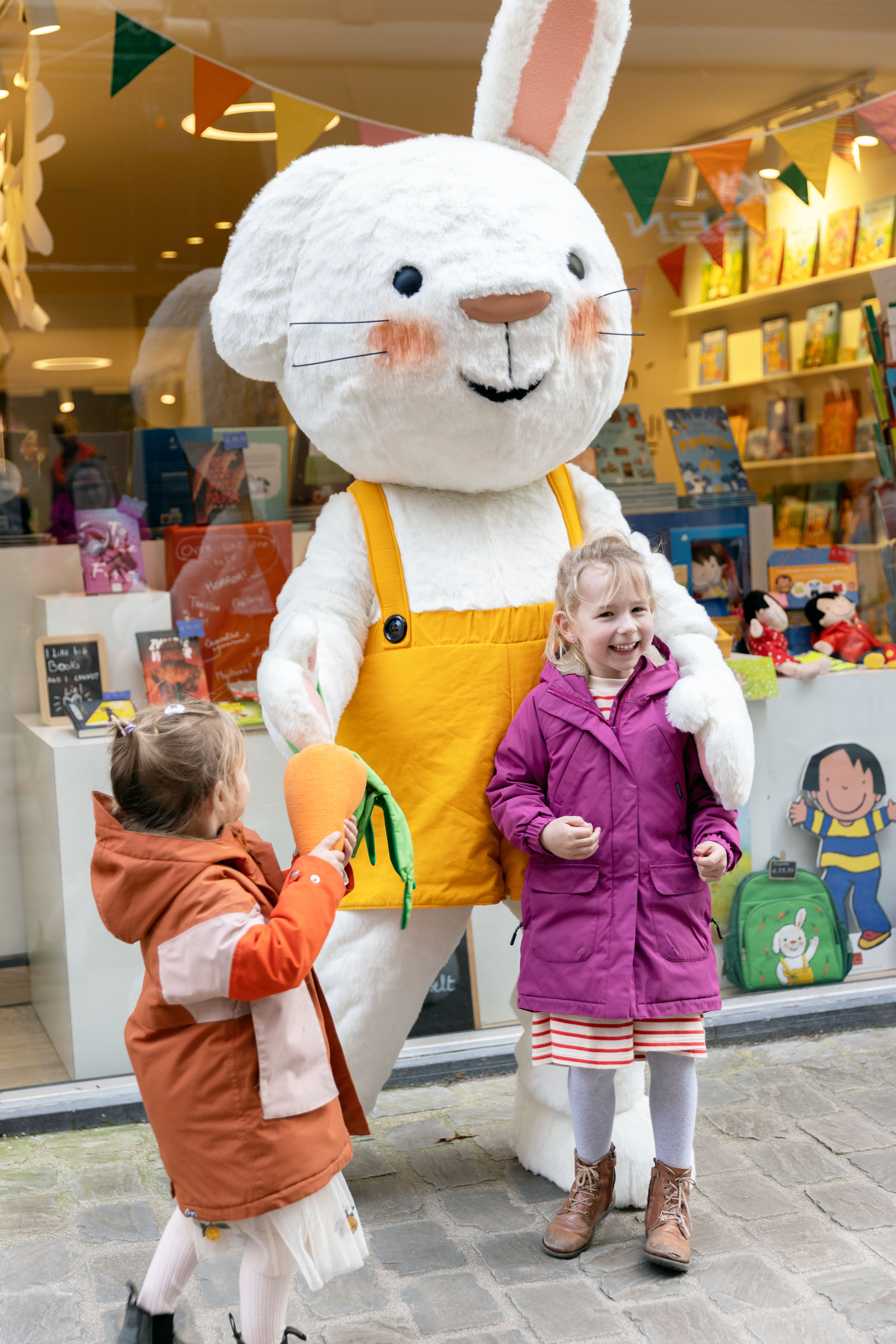 Een foto van twee kindjes die met Rikki op de foto gaan voor de etalage van Clavis Conceptwinkel.