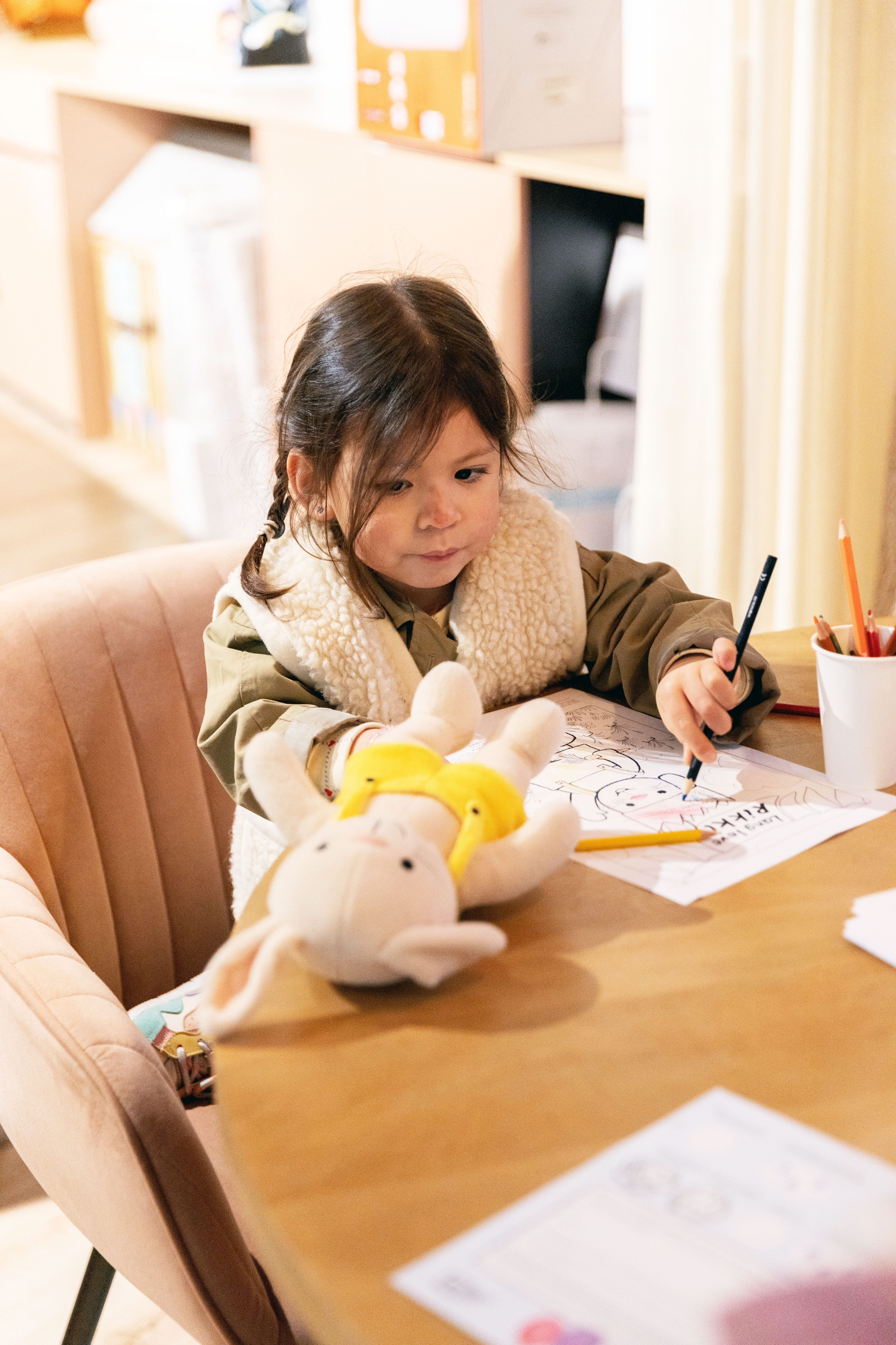 Een meisje kleurt een kleurplaat van Rikki is jarig in The Baby's Corner Hasselt. Ze heeft ook een knuffel van Rikki vast.
