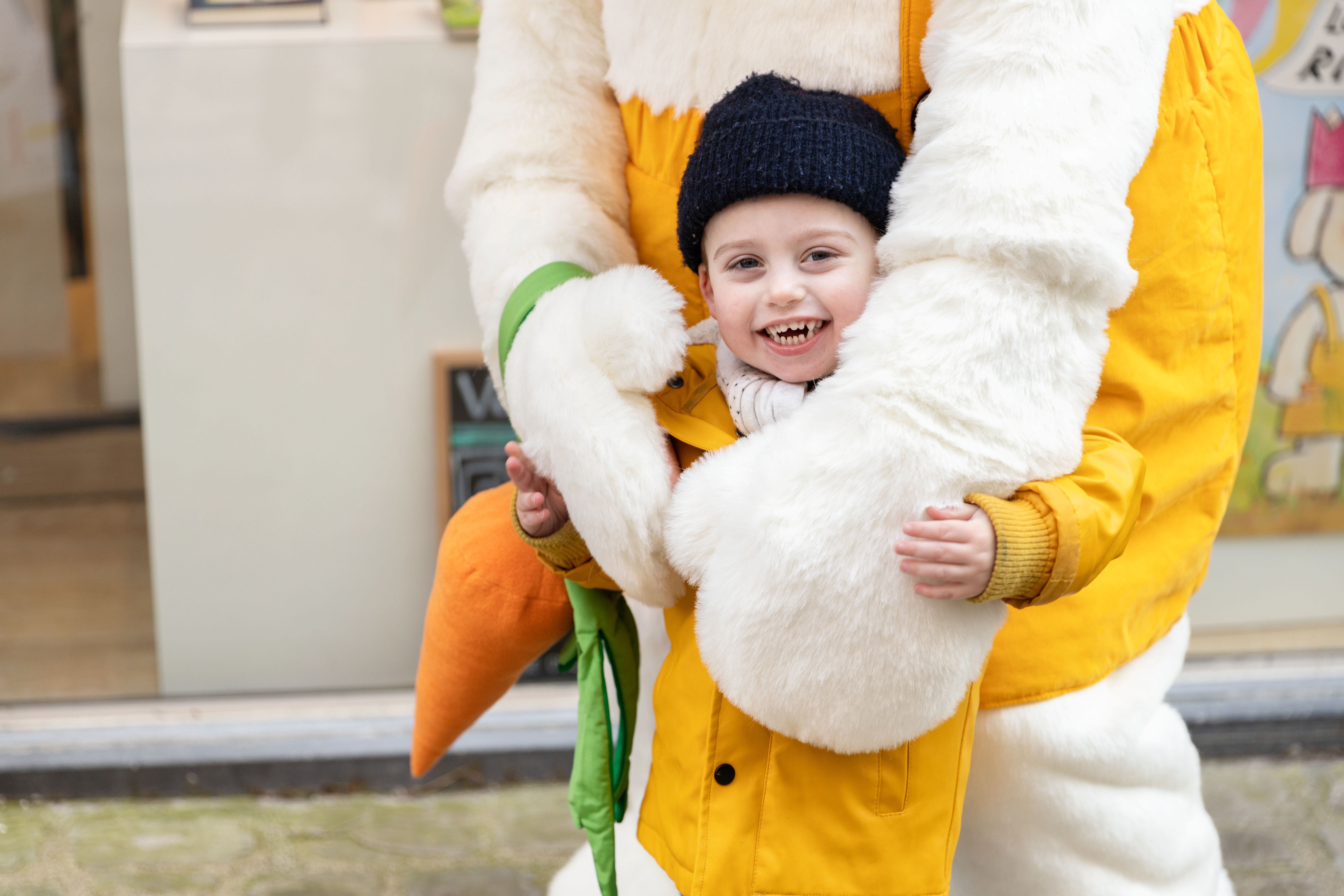 Een foto van een jongetje dat op de foto gaat met Rikki. het jongetje wordt geknuffeld door Rikki.