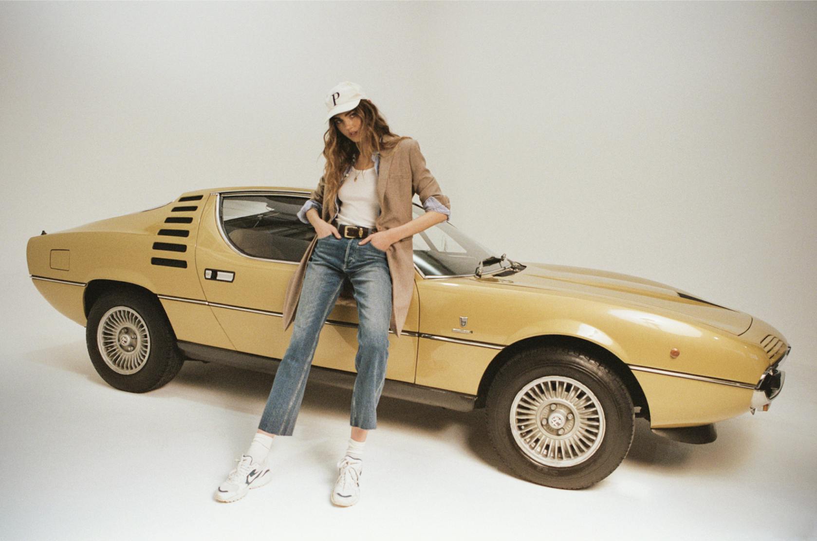 model standing beside yellow car