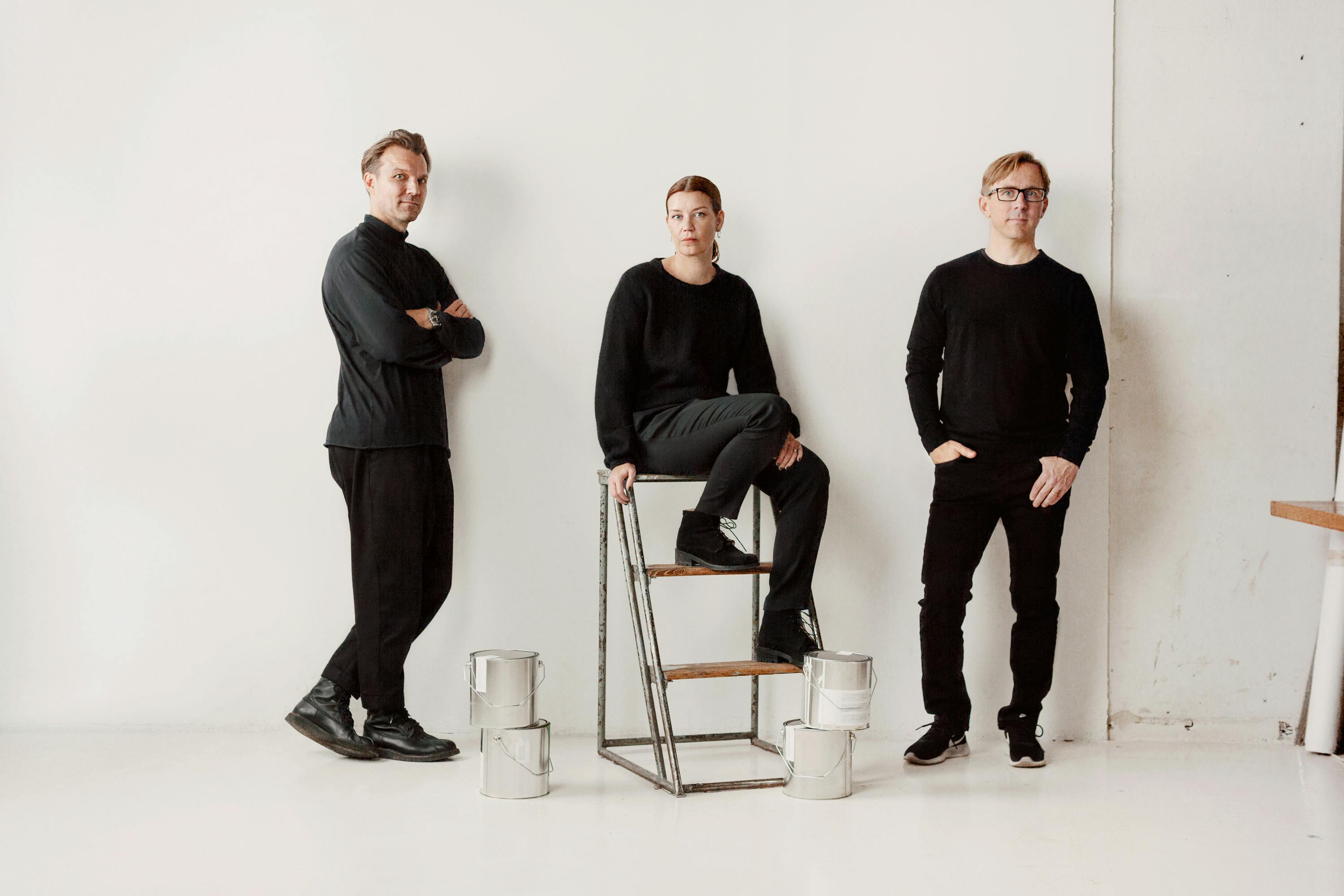 The founders of Cover Story pose behind a short stack of paint cans