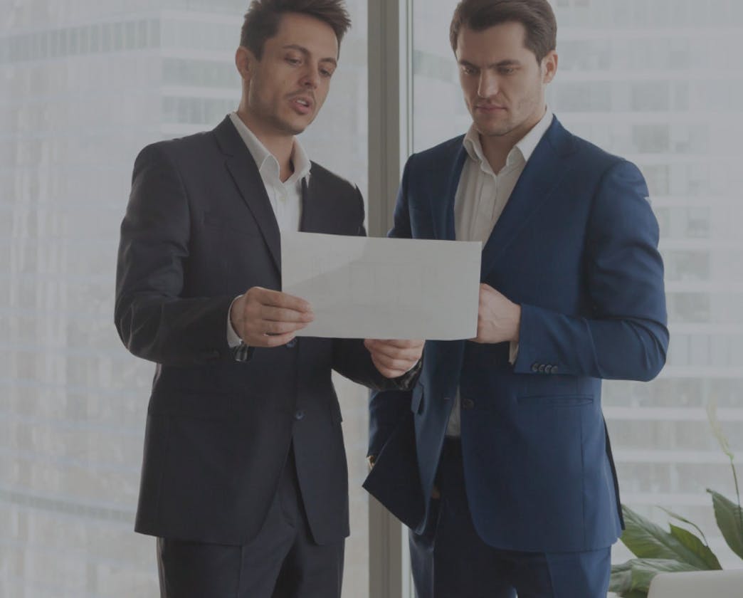 men in suits looking at document