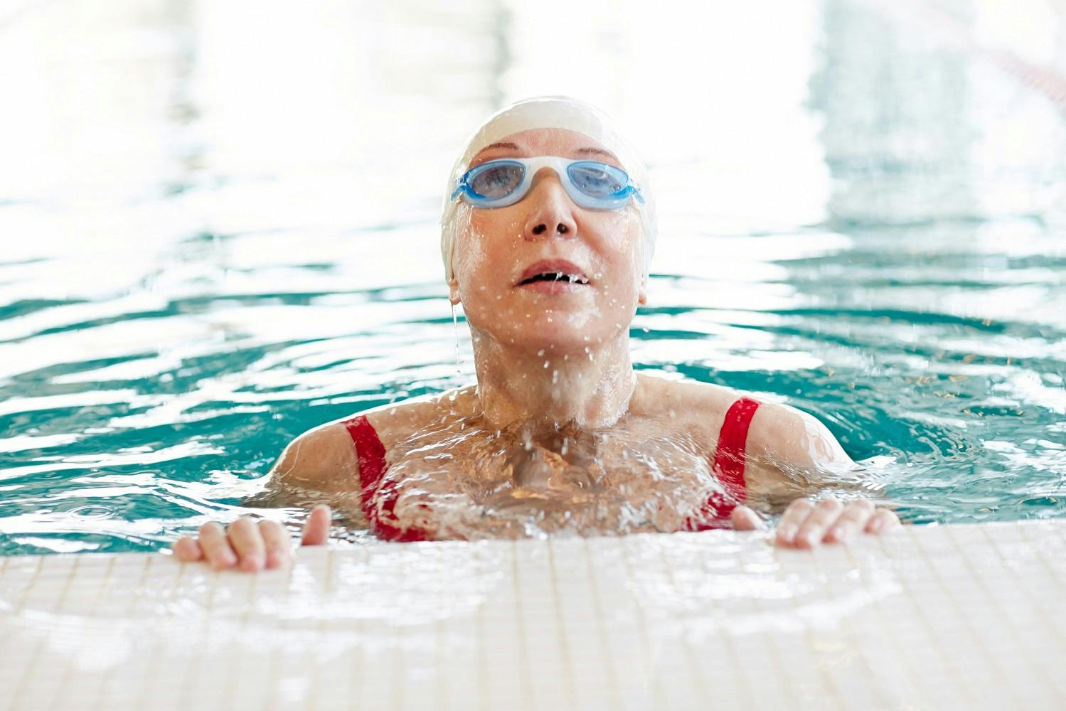 Mature woman in swim cap and goggles swimming