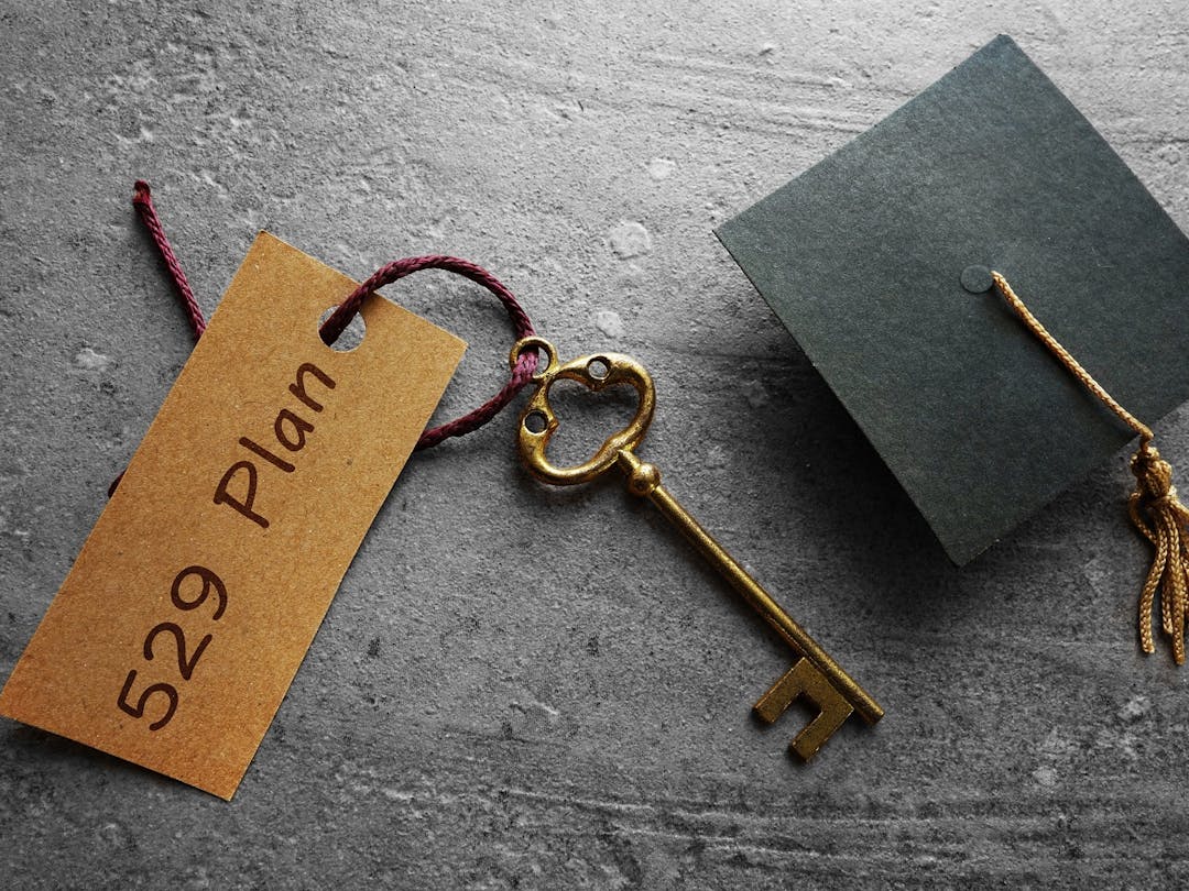 A graduation cap, old fashioned key, and sign that says 529 plan represents college savings