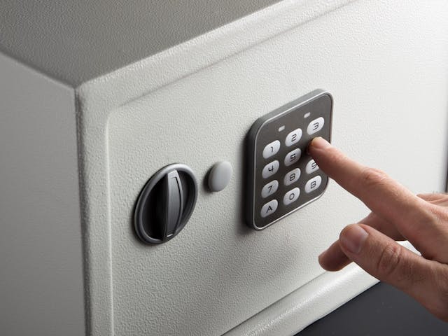 Closeup of a hand entering a code to open a safe