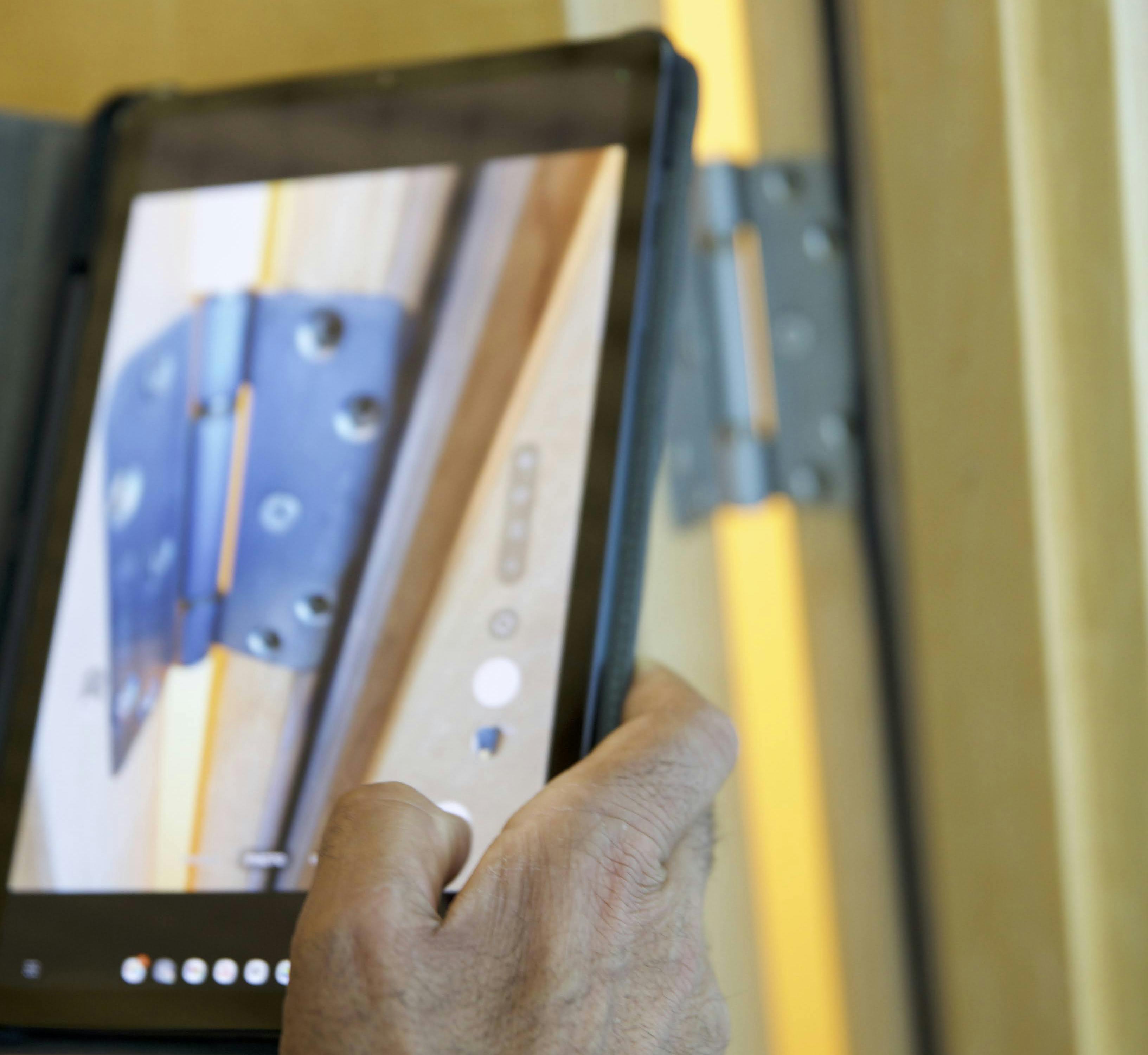 Inspector using hand held device to photograph door hinge