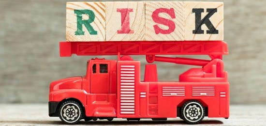 Toy firetruck with the word RISK spelled in wooden blocks