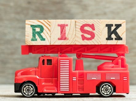 Toy firetruck with the word RISK spelled in wooden blocks