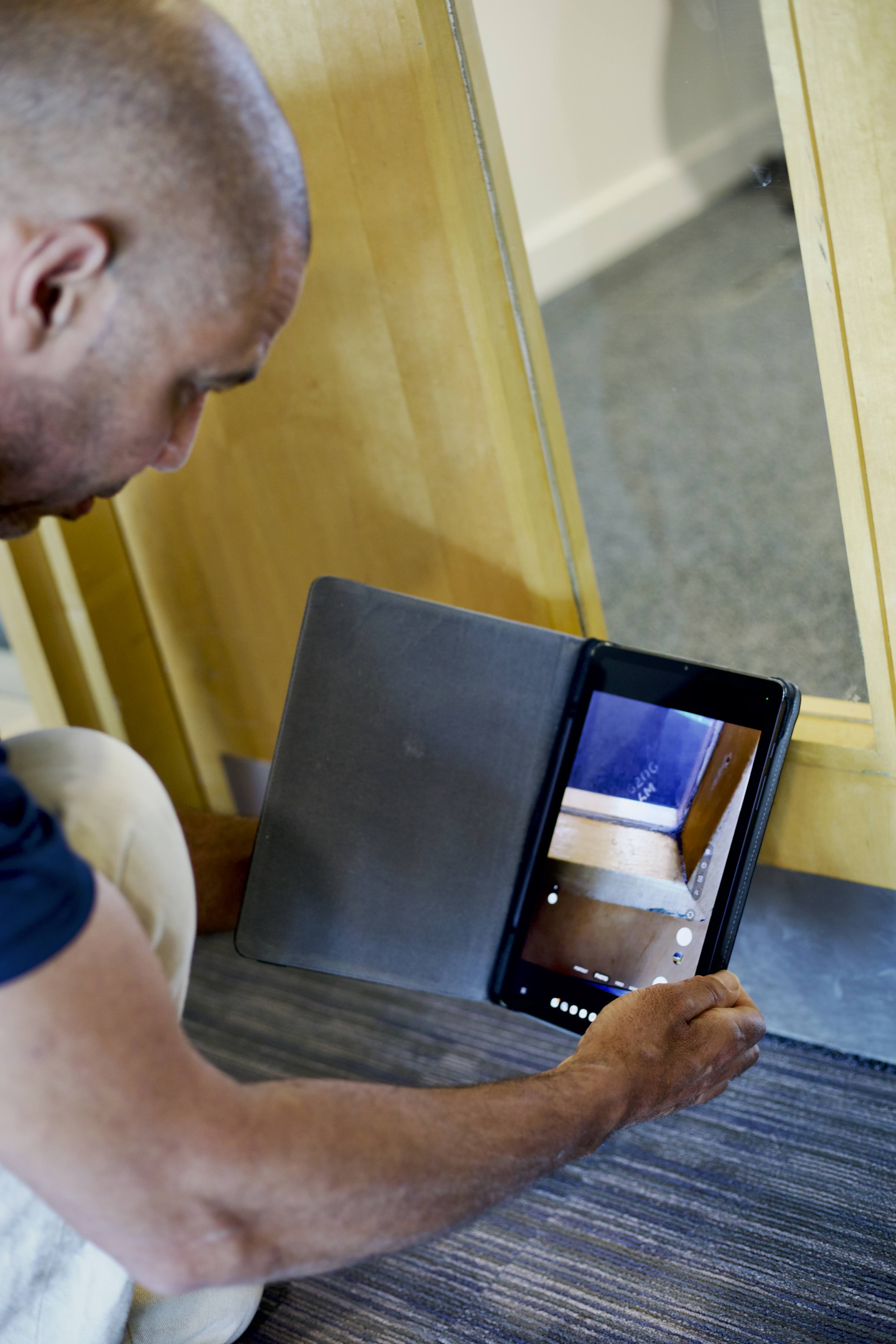 Inspector using a handheld device to take photo of fire door