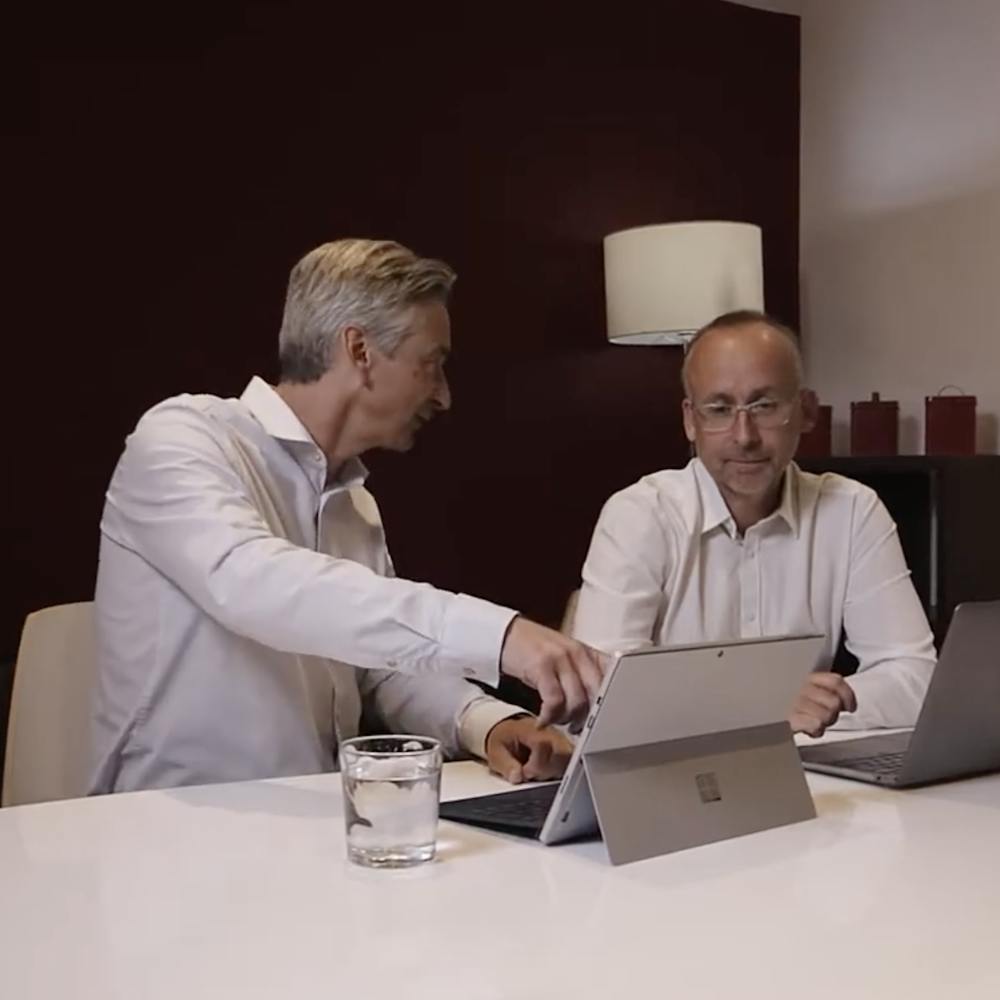 Matthew Westby and Stuart Letley of Clear seated at table, pointing at a surface tablet