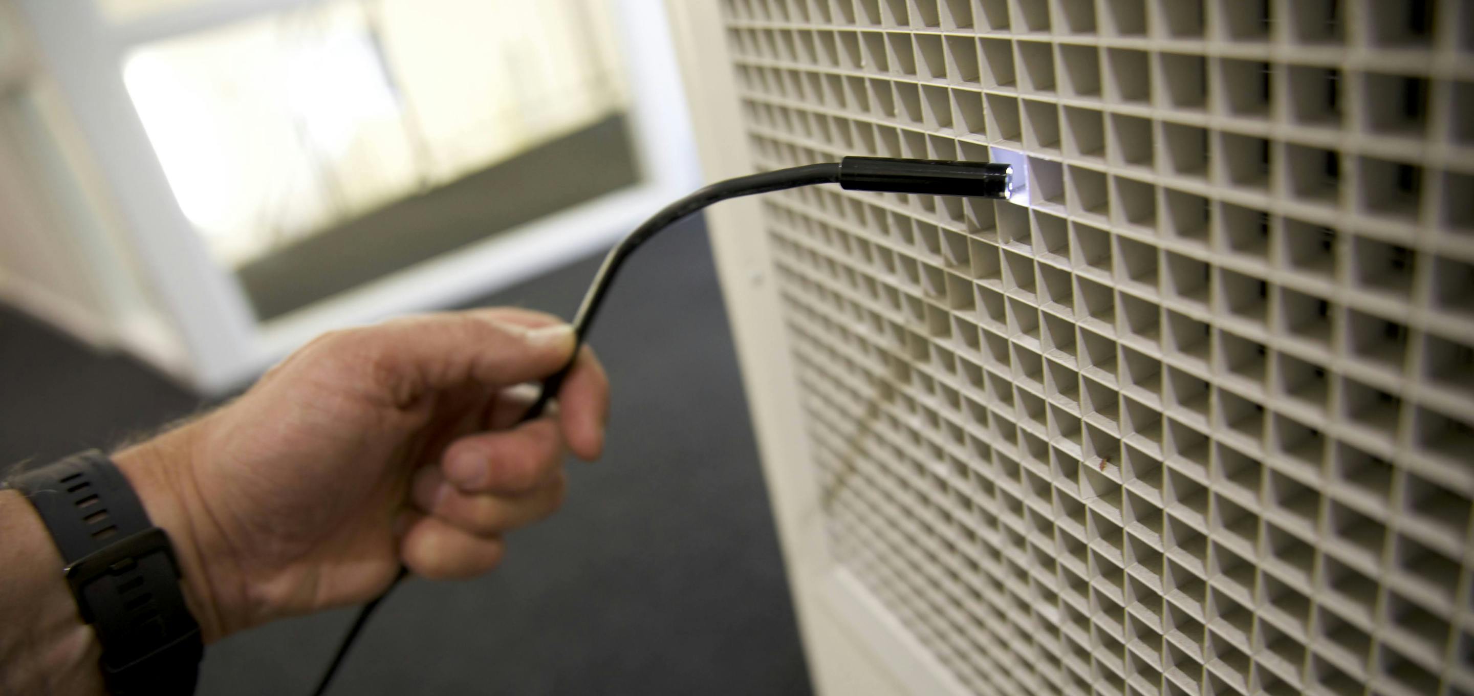 An image of a hand using a fibre optic camera to inspect a vent
