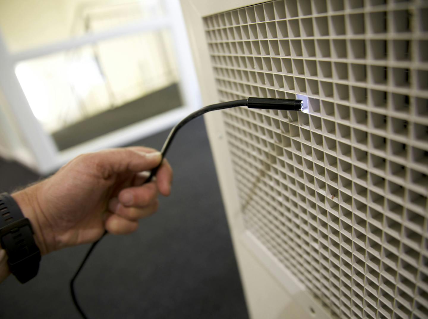 An image of a hand using a fibre optic camera to inspect a vent