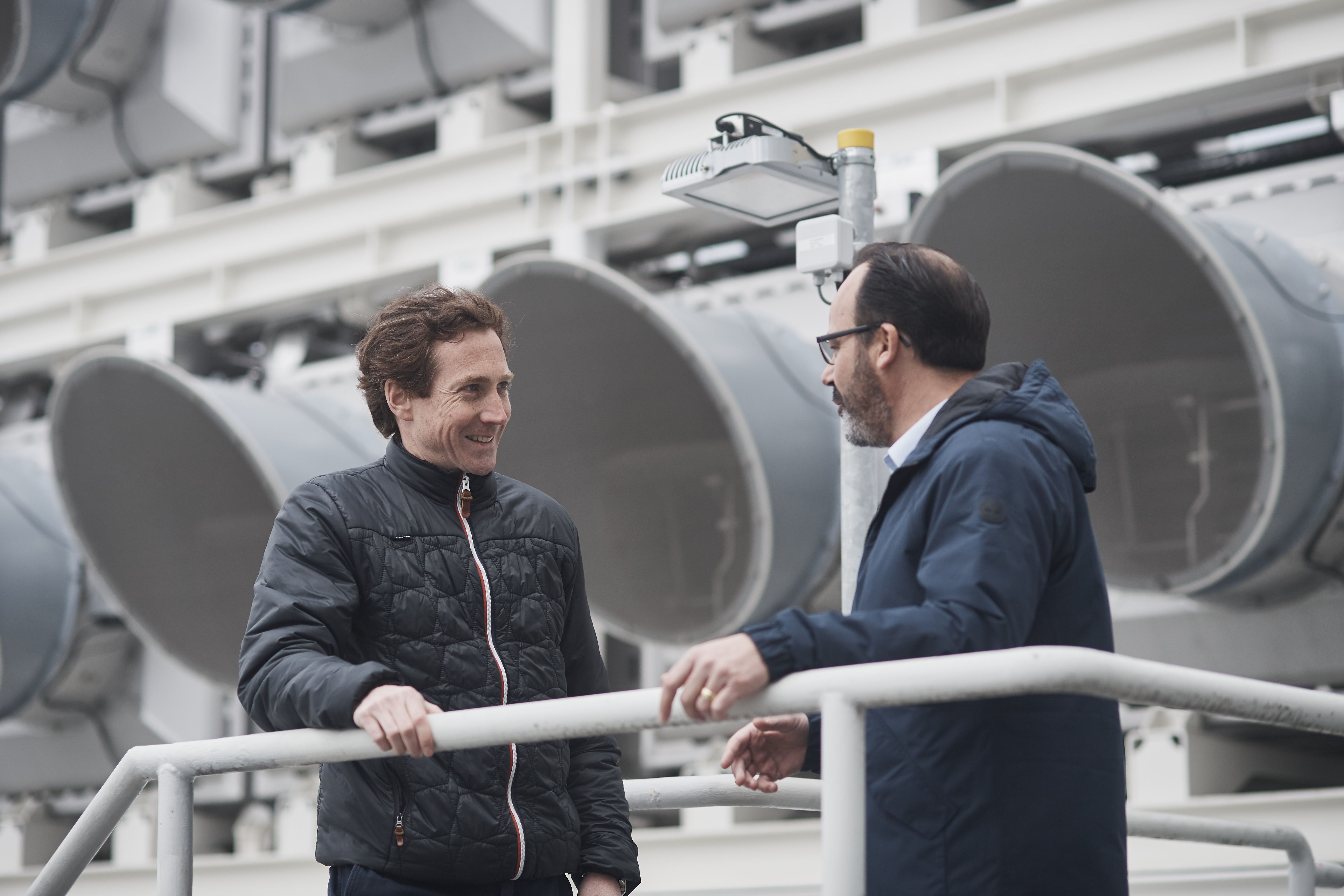 Two men standing next to DAC plant in Hinwil