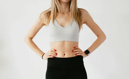 Jeune femme blonde debout avec ventre plat apparent.