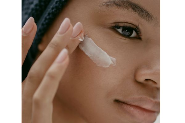Jeune femme qui s'applique de la crème sur le visage
