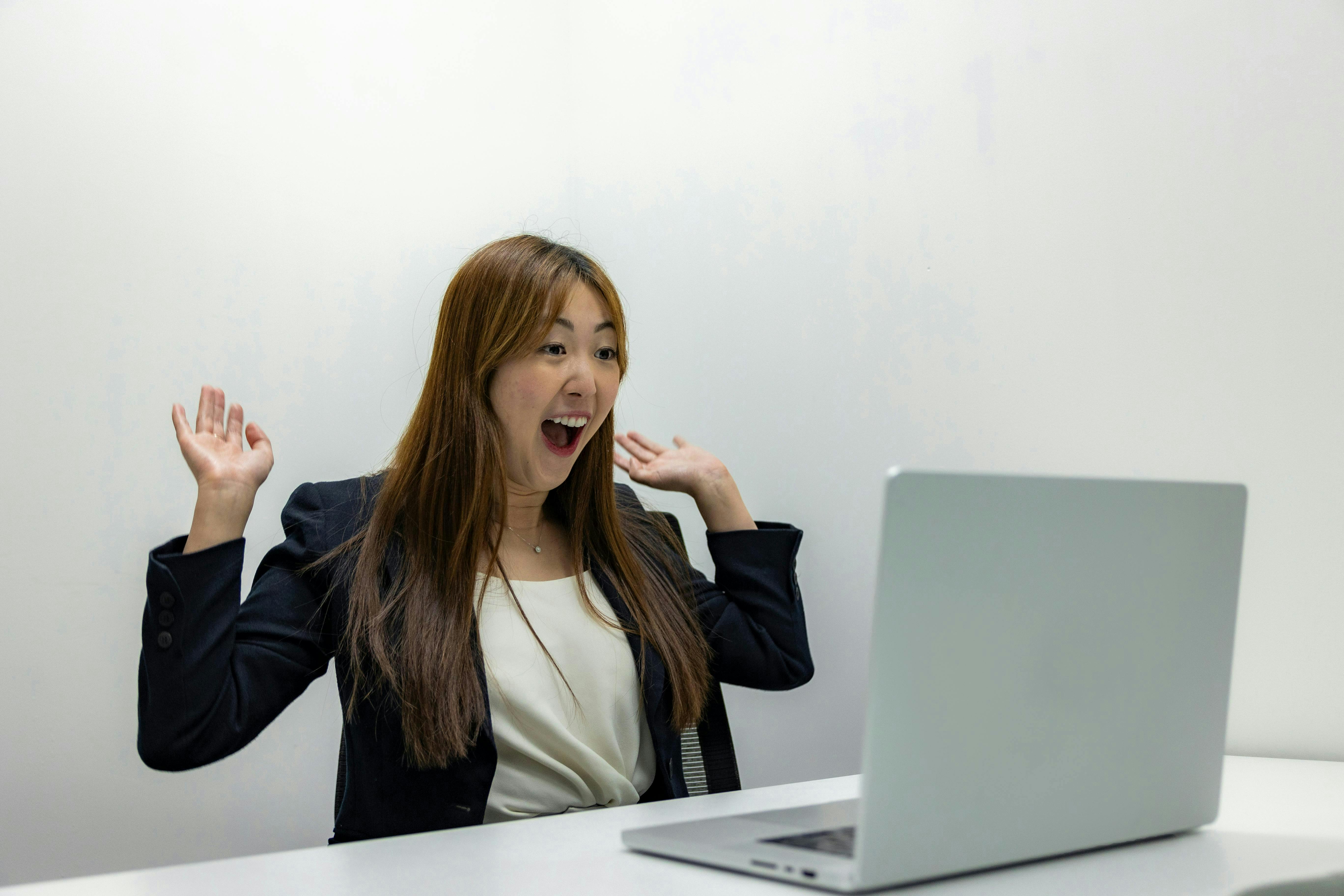 woman-celebrating-in-front-of-a-laptop-in-an-office