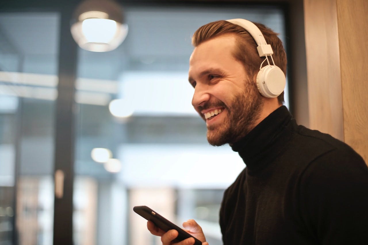 man with headphones smiling at phone
