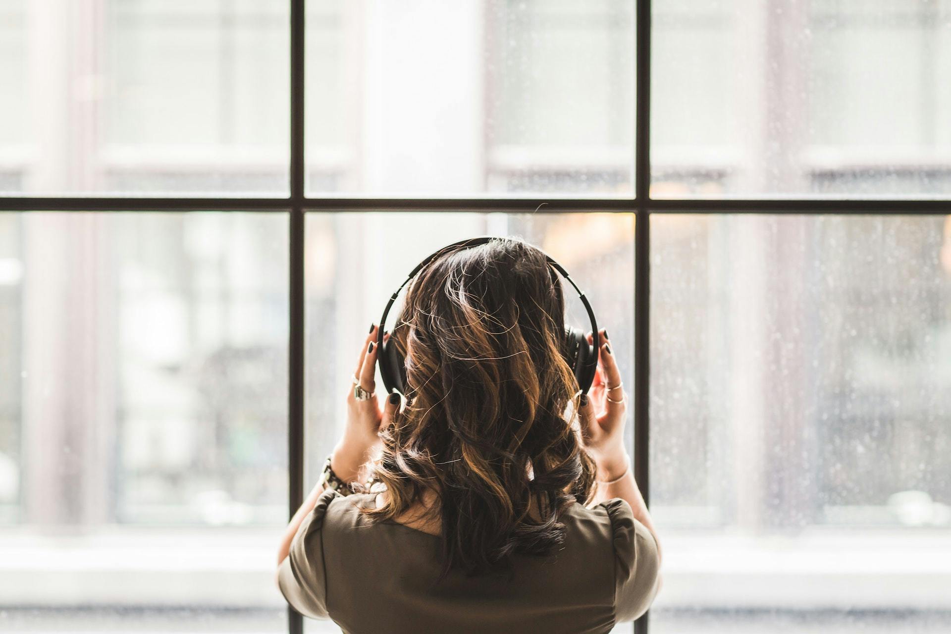 woman looking out the window with headphones