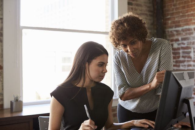 women working and looking at a computer monitor