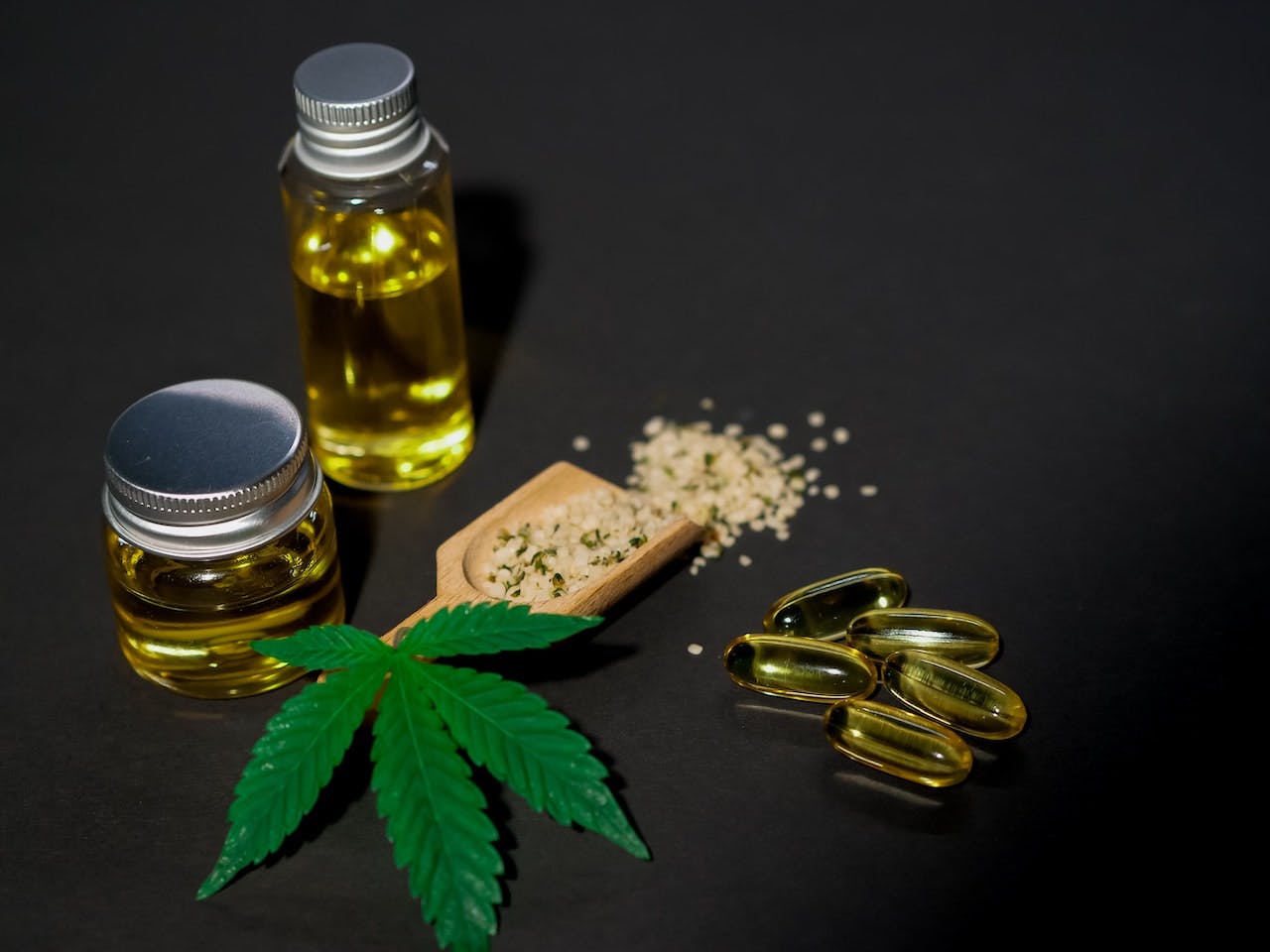 marijuana leaf next to jars of oil