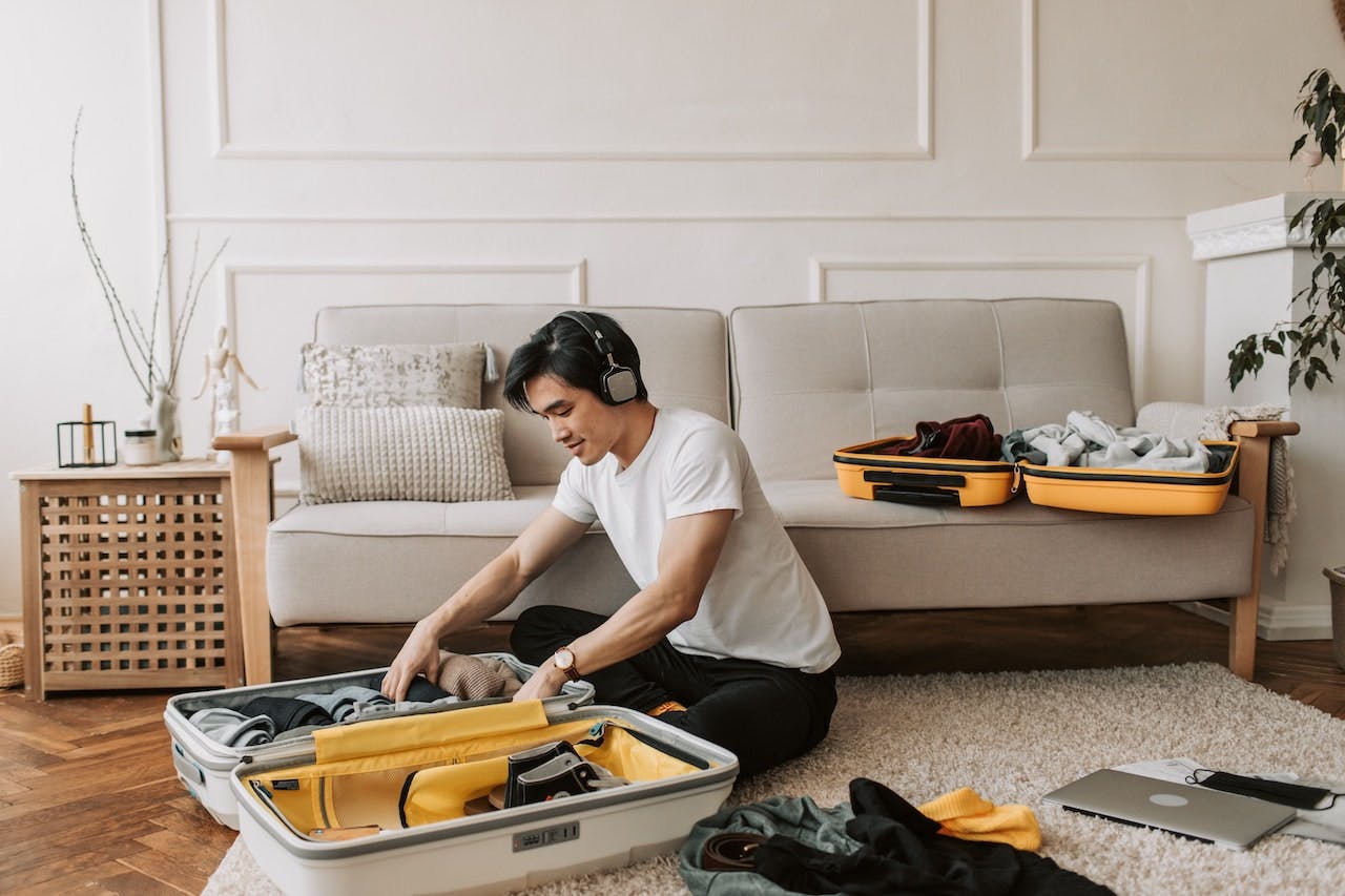 man with headphones packing a suitcase