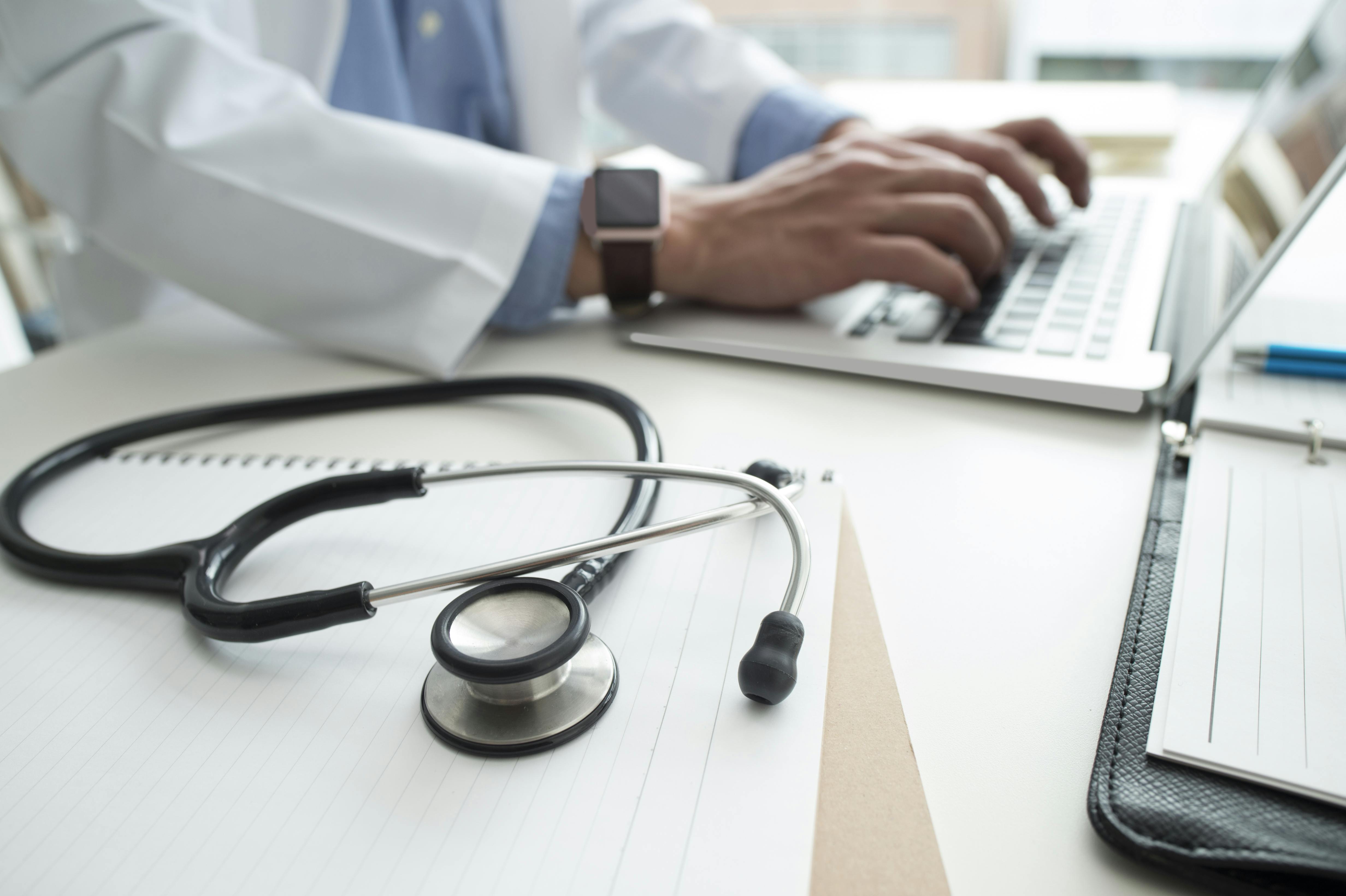typing on a laptop next to a stethoscope