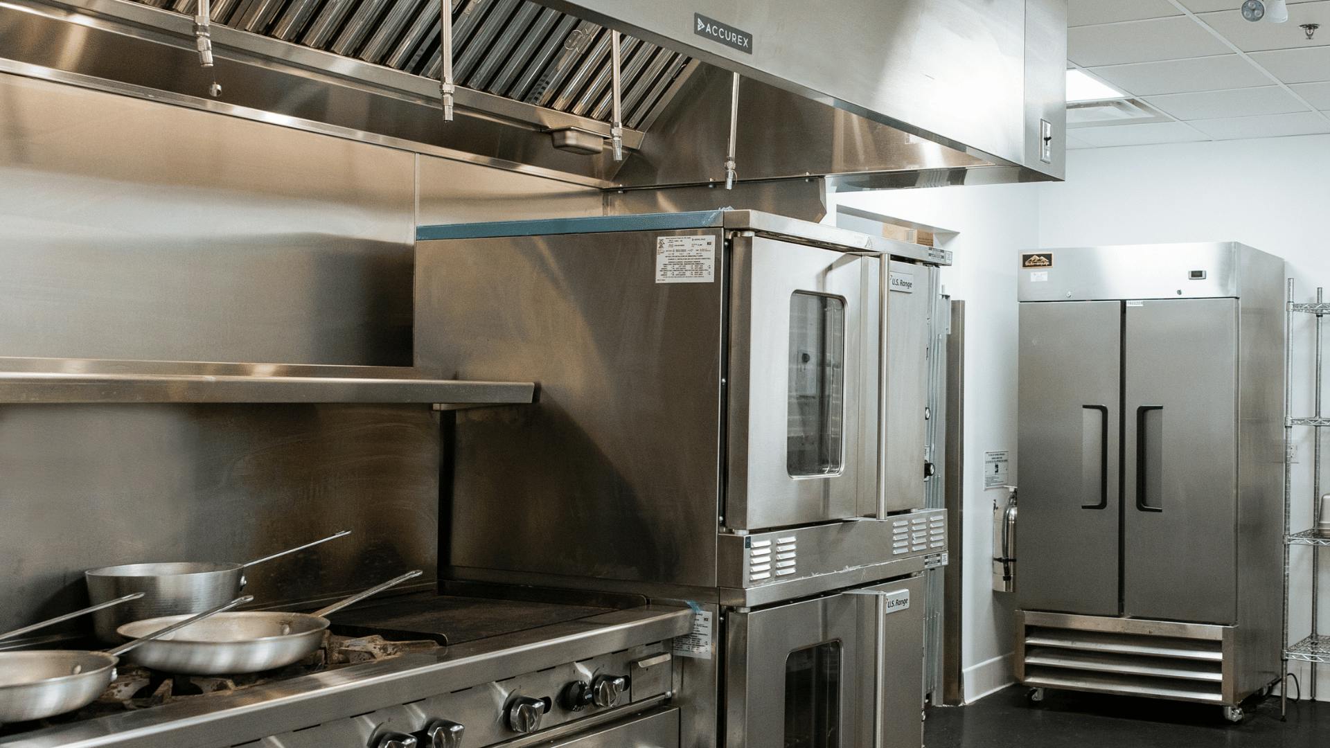 Professional kitchen with a stove, oven, freezer and pans, the walls and ceiling are white