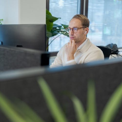 Hugo geconcentreerd aan het werk achter zijn bureau op het kantoor van Cloud++