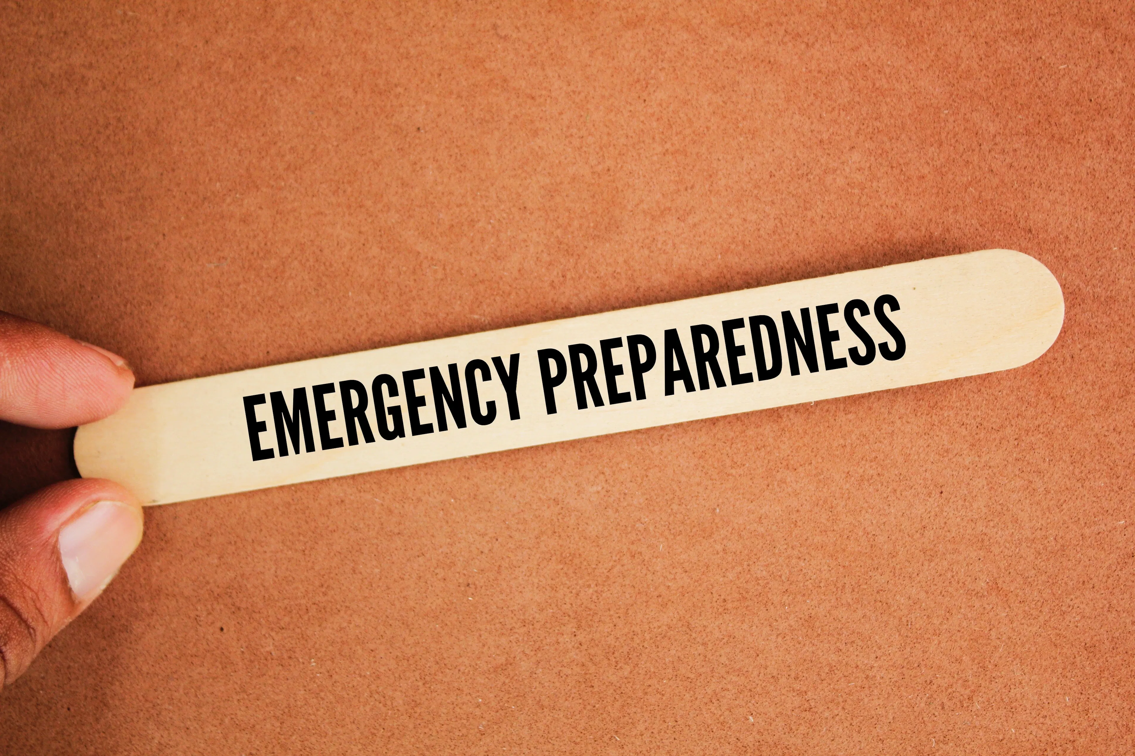 A person is holding a popsicle stick that says "Emergency Preparedness" in a healthcare context.