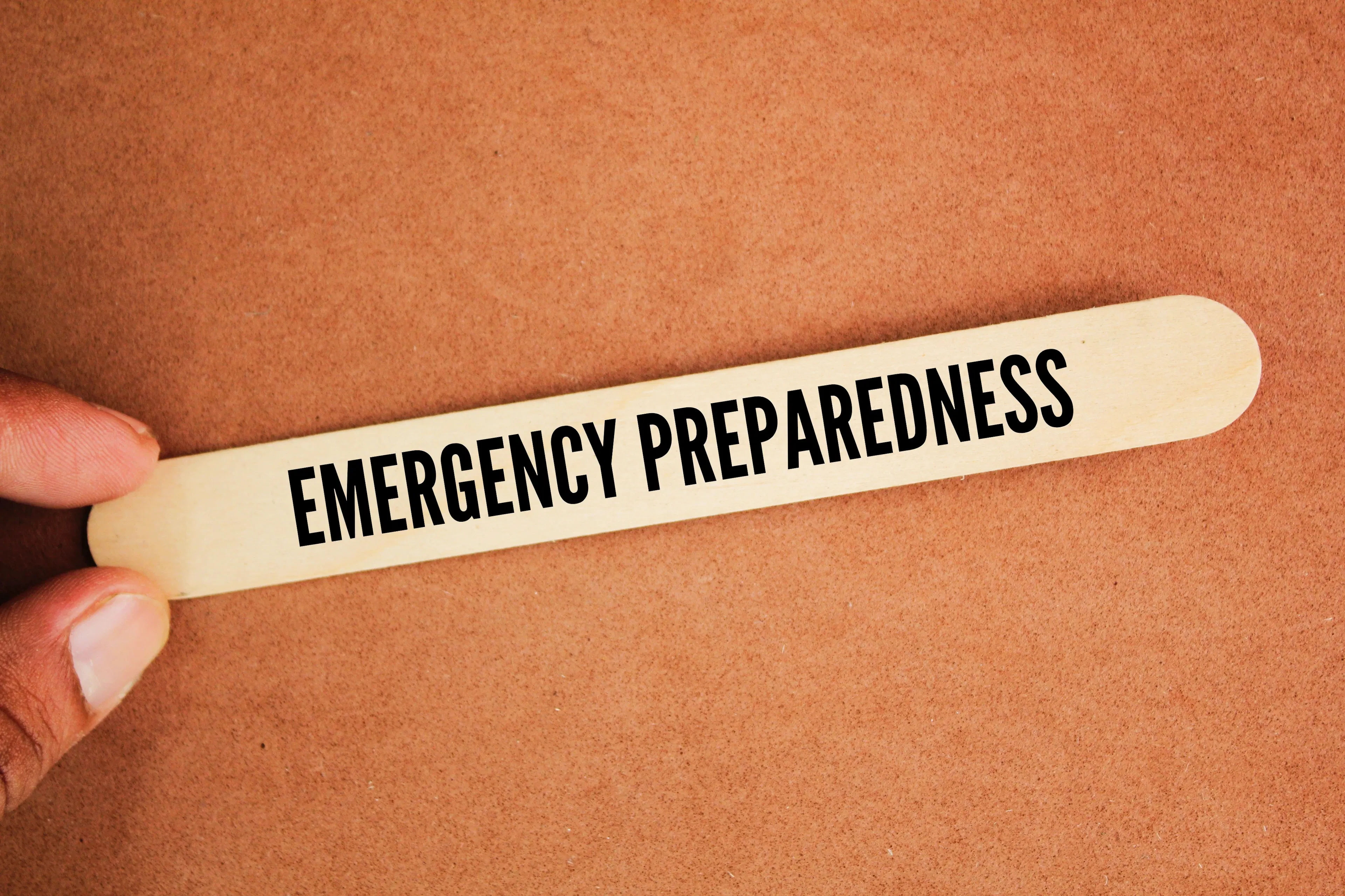 A person is holding a popsicle stick that says "Emergency Preparedness" in a healthcare context. 