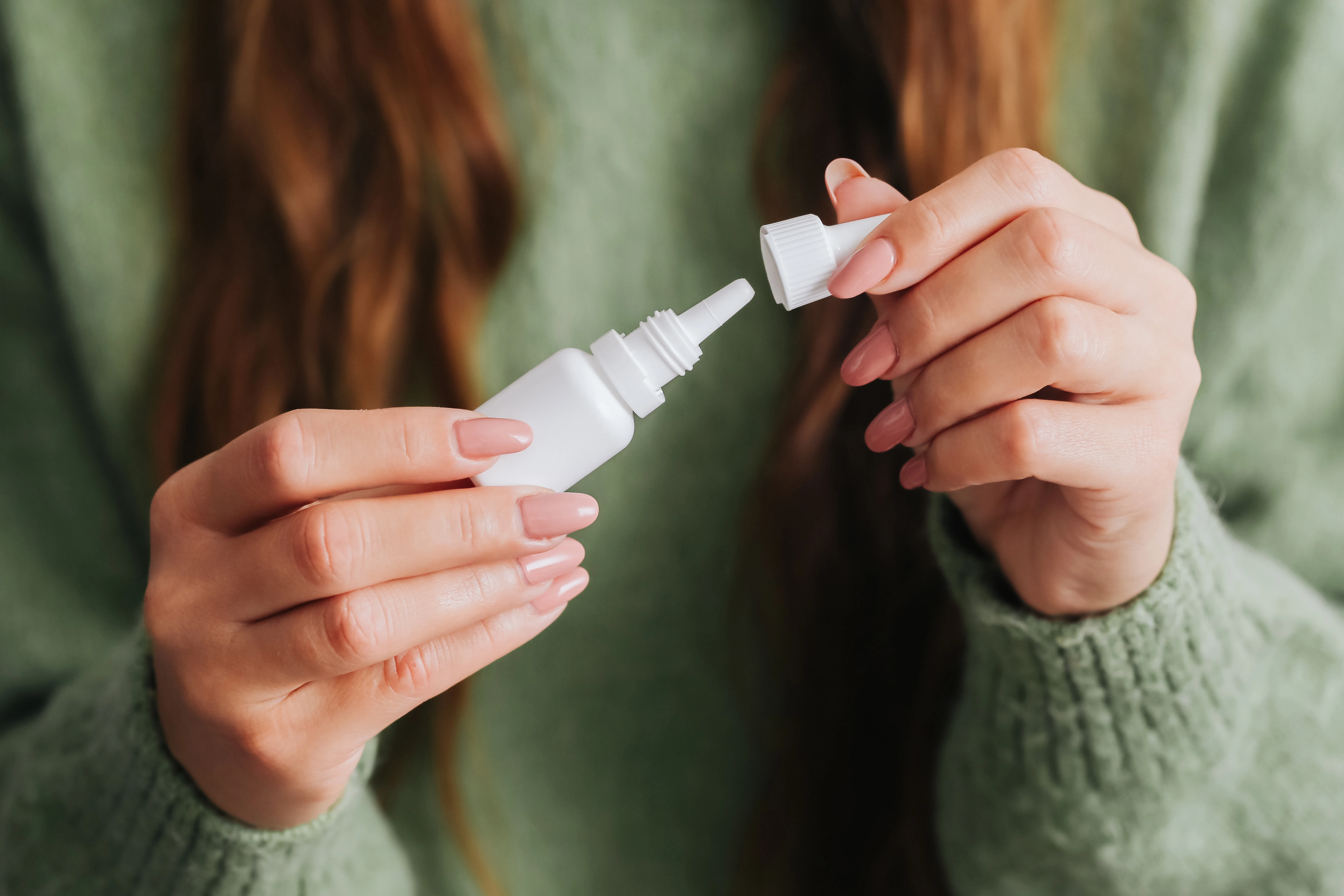 A woman is holding her allergy drops in her hands.